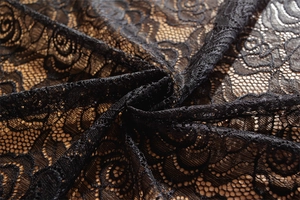 Macro shot of black rose lace fabric texture on brown wooden background for decor