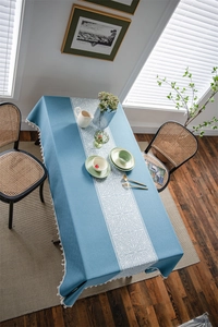 Detailed view of blue jacquard tablecloth with white floral pattern and fringe edge