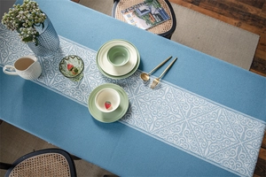 Close-up of blue jacquard tablecloth featuring white baroque pattern and fringe trim