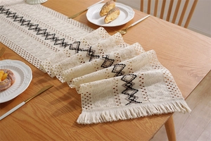 Détail du motif géométrique en losange et des franges d'un chemin de table en lin et coton