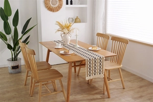 Détail d'un chemin de table en lin bohème avec motifs géométriques et pompons frangés