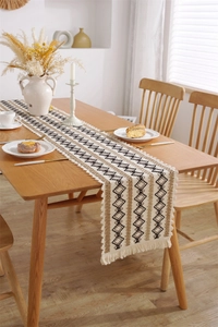 Gros plan d'un chemin de table bohème en lin avec motifs losanges et franges artisanales