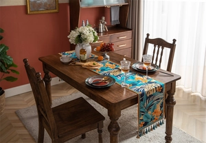 Détail d'un chemin de table tropical avec motifs de feuilles de monstera et glands bleus