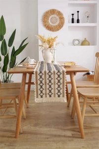 Gros plan du chemin de table en lin bohème avec motifs losanges et pompons