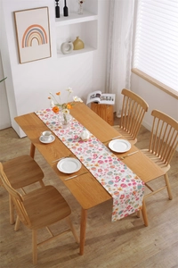 Detailed close-up of Easter table runner with colorful floral and egg print on light wood