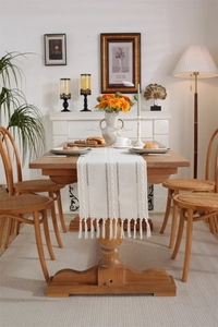 Detailed view of the hollow crochet texture and handmade tassels on the cream table runner