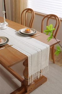 Detail of hollow jacquard table runner with textured cable knit and tassel fringe edge