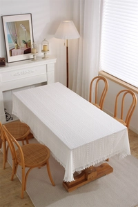 Close-up of white lace tablecloth featuring delicate hollow embroidery and tassel edges