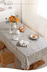 Dettaglio tovaglia in TPU impermeabile con motivi geometrici grigi e nappe bianche
