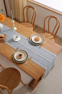 Close-up of blue textured table runner with white geometric embroidery and fringe