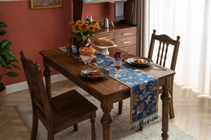 Détail d'un chemin de table jacquard bleu aux motifs tropicaux et bordures de pompons