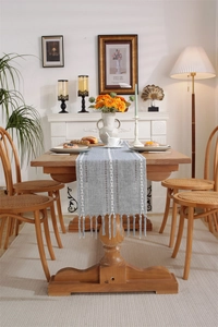 Close-up of blue-gray jacquard table runner with white woven patterns and tassel fringe