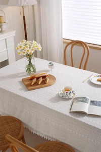 Close-up of white floral lace embroidery and scalloped edges on cotton tablecloth
