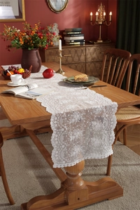 Nahaufnahme weißer Spitzen-Tischläufer mit Blumenstickerei und Wellenrand auf Holztisch