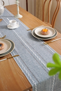 Close-up of blue jacquard table runner featuring white embroidery and hollow-out stripes