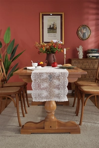 Detailansicht weißer Tischläufer aus Spitze mit floraler Stickerei auf einem Holztisch