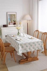 Detailed view of floral cotton tablecloth featuring pink flowers and white pom-pom fringe