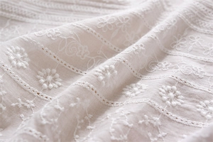 Close-up of white cotton lace tablecloth with hollow embroidery and floral texture