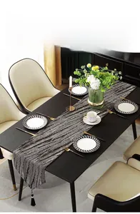 Macro detail of luxury jacquard table runner featuring abstract wood grain and black tassels