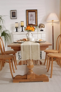 Macro detail of beige boho table runner featuring white woven stripes and handmade tassels