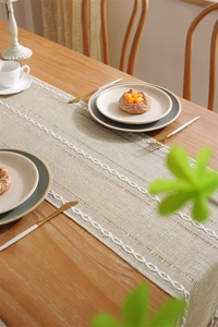 Macro detail of beige hollow out jacquard table runner with leaf embroidery and tassels