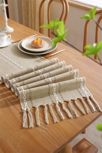 Detail of bohemian jacquard table runner with textured embroidery and tassel fringe