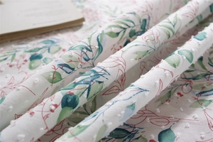 Macro shot of white cotton tablecloth with green leaf print and clip spot texture detail