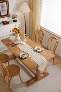 Detailed crochet hollow lace table runner with tassels on a wooden dining table