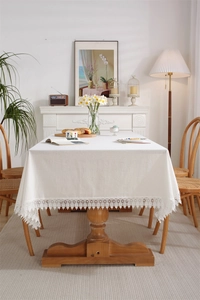 Detailed close-up of white cotton lace tablecloth edge with elegant hollow embroidery