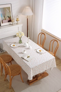 Close-up of floral cotton tablecloth featuring pink flower prints and white pom-pom trim