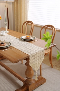 Close-up of vintage crochet table runner with geometric lace and beige tassels