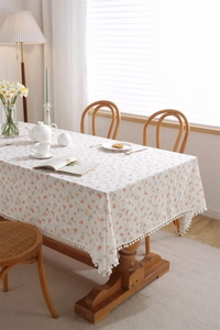Close-up of floral print cotton tablecloth with decorative white pom-pom fringe details