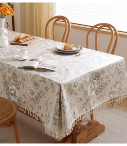 Dettaglio di tovaglia impermeabile con motivi floreali retrò ed eleganti nappe beige