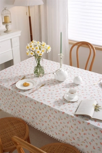 Detailed view of floral tablecloth featuring 3D dot texture and white pom-pom fringe trim