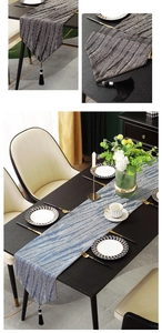 Close-up of modern jacquard table runner with feather texture and elegant black tassels
