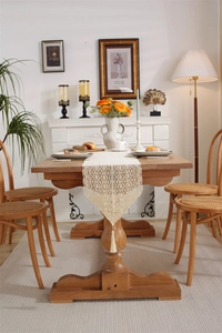 Detail of crochet hollow table runner with fringe tassels on a wooden dining table