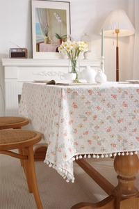 Close-up of floral cotton tablecloth with 3D dot texture and white pom-pom fringe