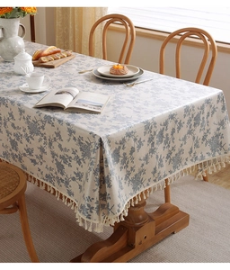 Dettaglio del motivo floreale retrò e delle frange con nappe sulla tovaglia in cotone e lino
