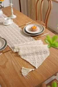 Detail of crochet table runner with openwork floral patterns and elegant tassels