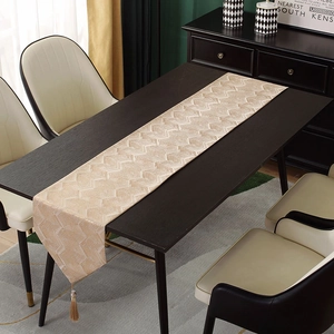 Close-up of golden geometric jacquard table runner with elegant fringe tassels
