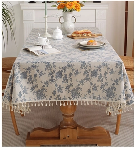 Dettaglio della tovaglia impermeabile con motivi floreali blu e nappe decorative beige