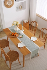 Close-up of geometric jacquard table runner with tassels on a rustic wooden dining table