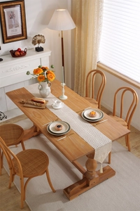 Detail view of a beige lace crochet table runner with tassels on a wooden dining table