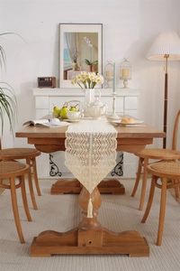 Close-up of beige crochet hollow table runner with elegant lace fringe and tassels