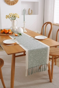Detailed view of sage green jacquard table runner with bohemian patterns and tassels