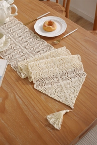 Detail of crochet lace table runner with hollow floral patterns and long tassels