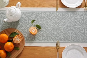 Close-up of jacquard table runner with damask pattern and elegant tassels on wooden table