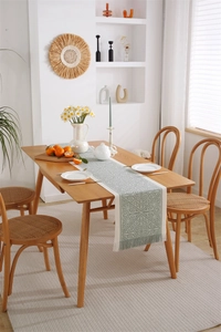 Detailed view of woven jacquard table runner with fringe tassels on a wooden dining table
