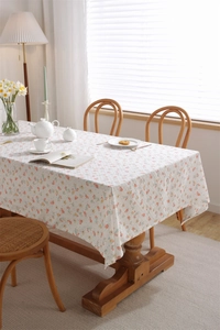 Detail of floral cotton tablecloth featuring orange blossoms and soft leaf patterns