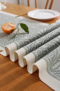 Close-up of jacquard table runner with green and beige classical scroll patterns